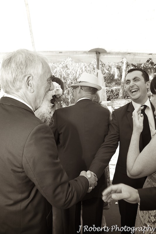 Groom being congratulated by his father in law after marriage ceremony - wedding photography sydney